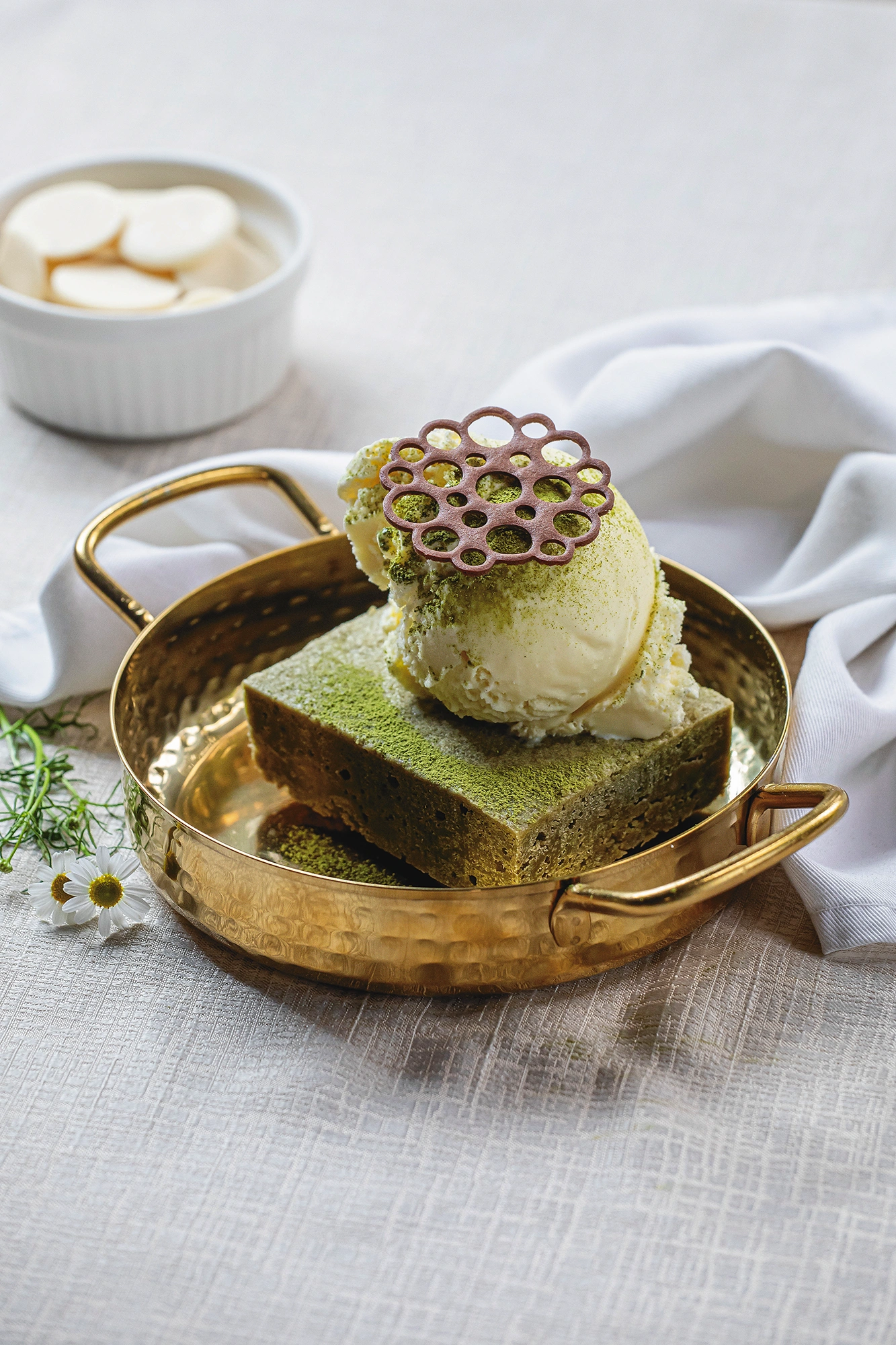 Brownie de matcha con helado encima y una filigrana de chocolate, servido en una bandeja dorada