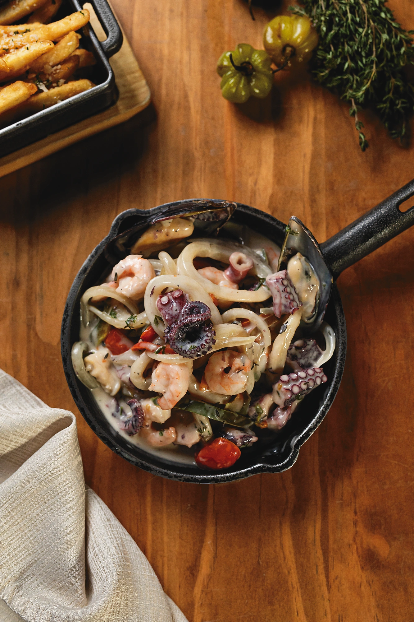 Cazuela de mariscos con camarones, calamar, pulpo y mejillones en salsa cremosa, servida en sartén de hierro
