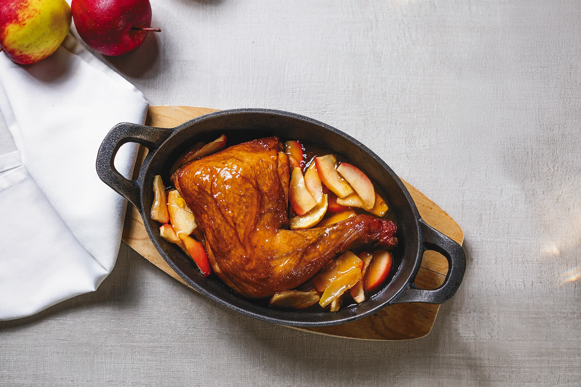Cuarto de pollo ahumado con manzanas caramelizadas, servido en una cazuela ovalada de hierro