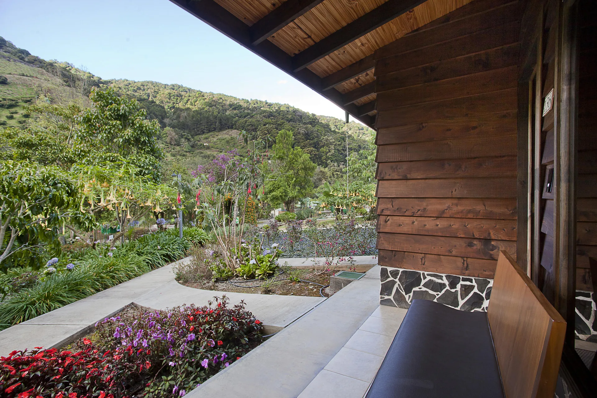 The view from the terrace towards the valley, with the wooden wall and bench to one side and the forested mountains beyond.