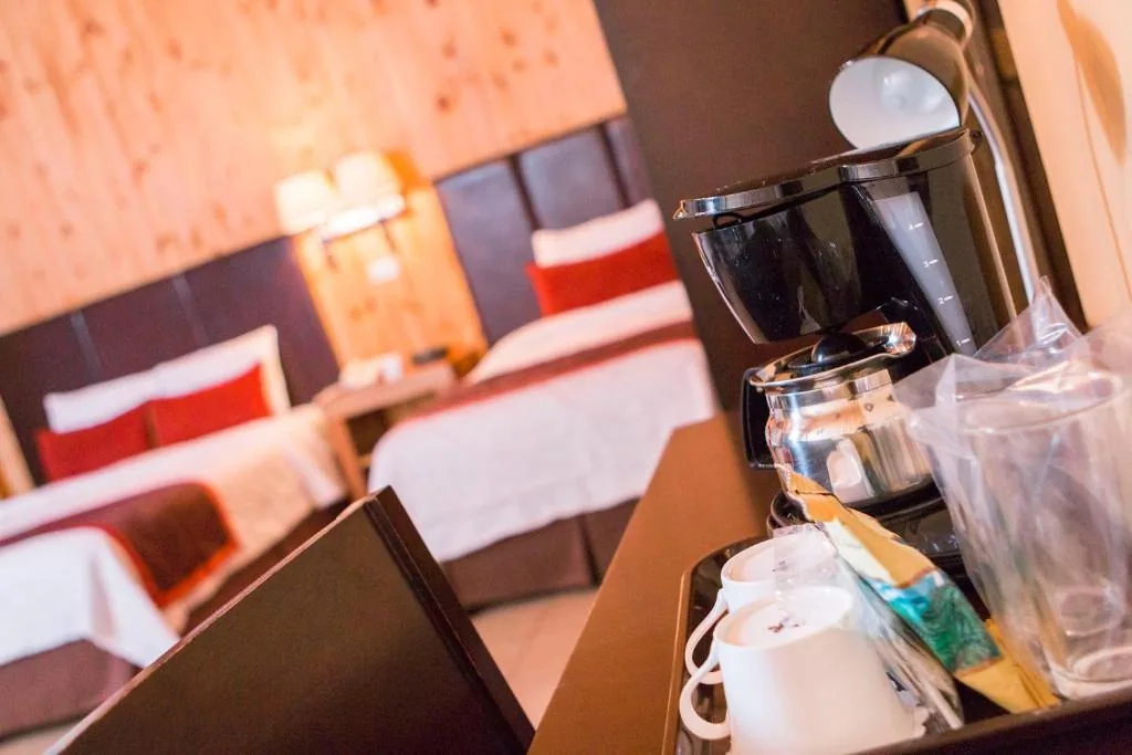 A coffee maker, cups and tea sachets on the room’s sideboard, with the two beds out of focus behind.
