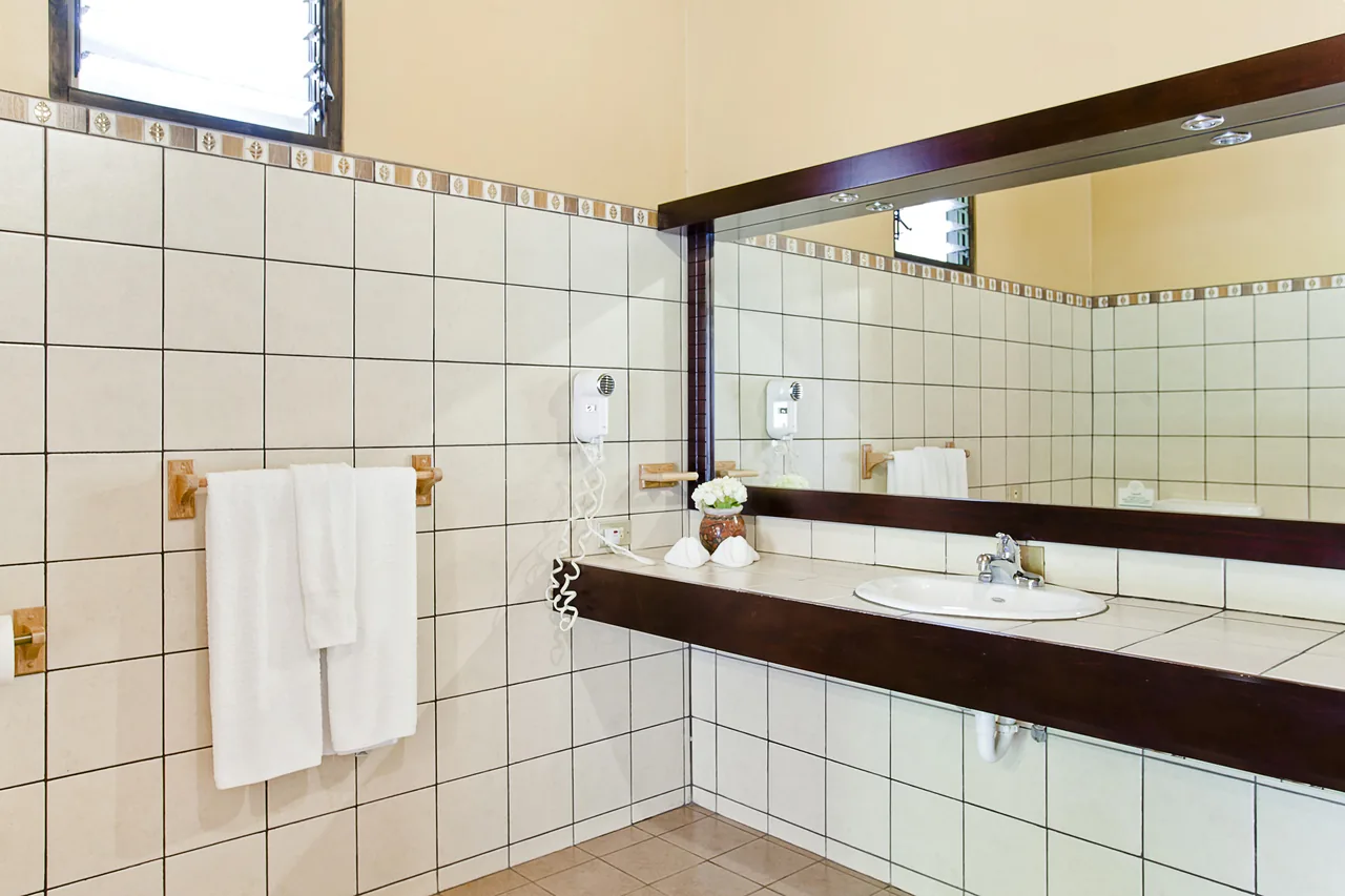The Junior Suite bathroom, with a built-in counter, a large mirror and a tub by the window